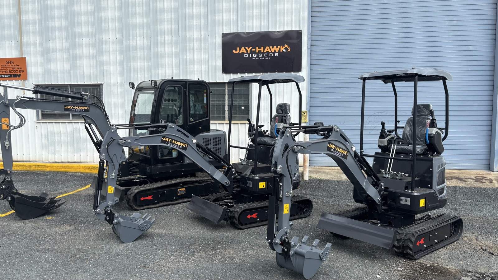 Three Jay-Hawk excavators lined up under the gold JAY-HAWK DIGGERS sign at the Arana Hills yard