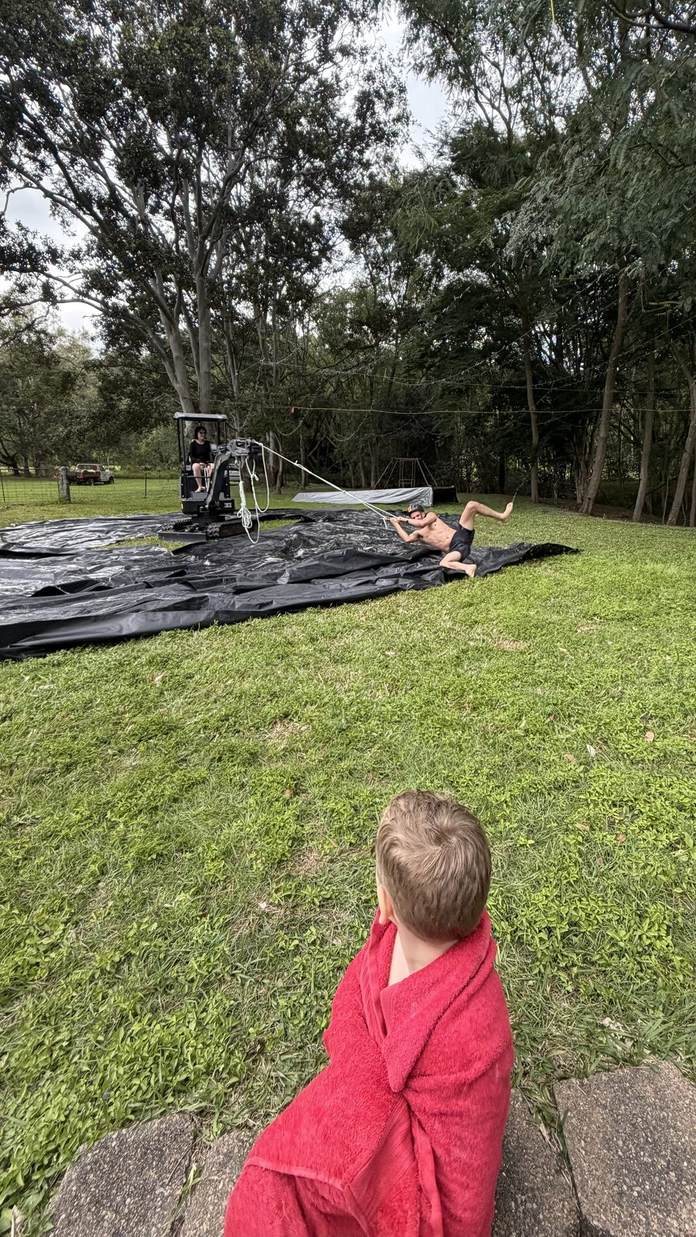Jay-Hawk mini excavator towing a slip and slide across the lawn, family fun at the yard