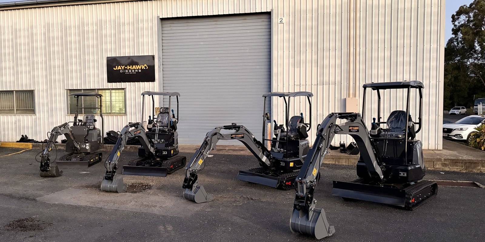 Five Jay-Hawk excavators lined up outside the Arana Hills workshop at sunset